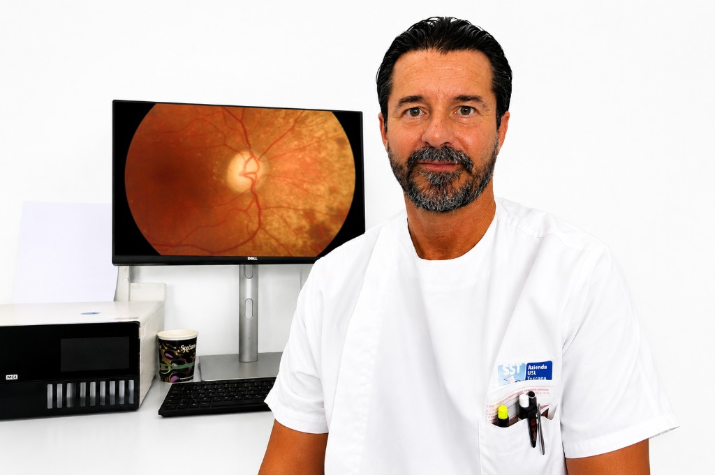 Dott. Daniele Galli in ambulatorio con immagine retinica sul monitor
